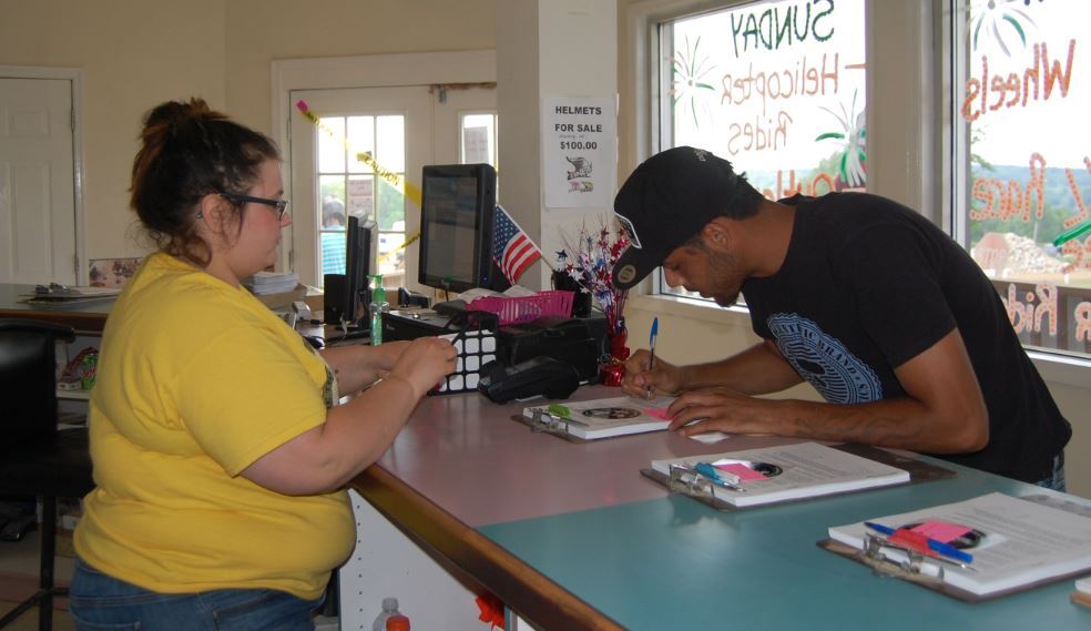 Man signing form from lady checking him in